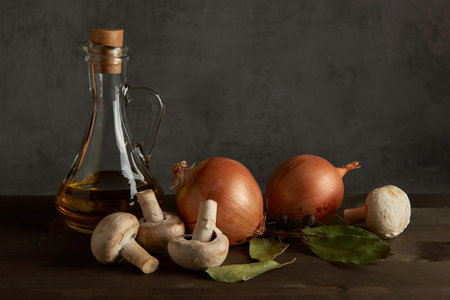Rural still life of vegetables and glass jug. On a wooden table is onion and mushroomsの写真素材