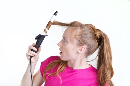 Girl in pink dress using curling isolated on whiteの写真素材