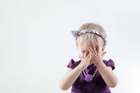 Little girl in violet dress close her face isolated on whiteの写真素材