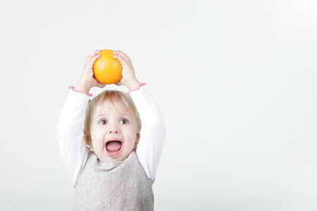 Little screaming girl with orange isolated on whiteの写真素材