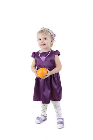 Little girl with orange in violet dress isolated on whiteの写真素材