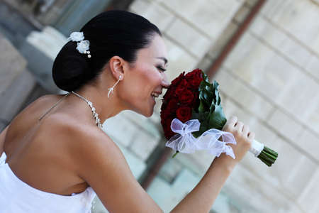 beautiful bride with red roses near the wallの写真素材