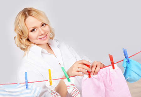 Woman hanging baby laundry to the ropeの写真素材