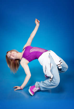 Beautiful girl dancing hip-hop isolated on blue backgroundの写真素材
