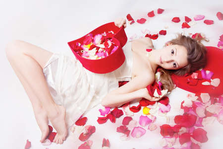Beautiful girl with rose petals in heart form boxの写真素材