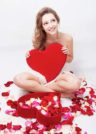Beautiful girl with rose petals in heart form boxの写真素材