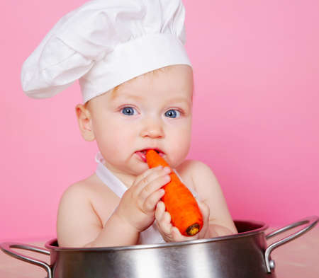 Baby cook eating carrot in studioの写真素材