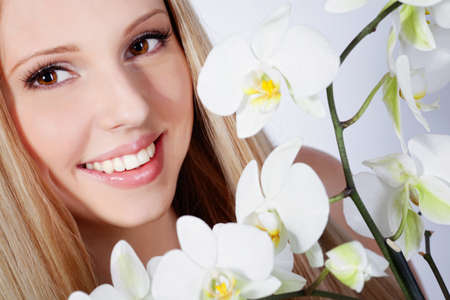 Beautiful blond girl with orchid flower in studioの写真素材
