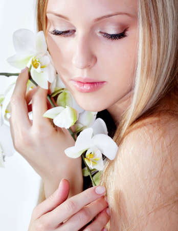 Beautiful blond girl with orchid flower in studioの写真素材