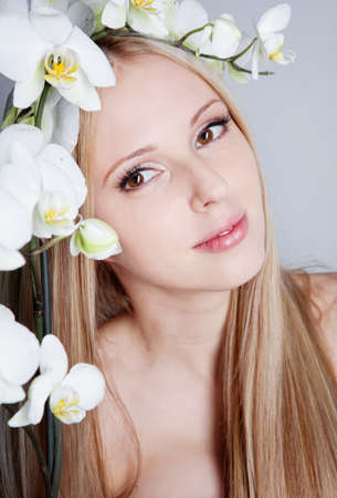 Beautiful blond girl with orchid flower in studioの写真素材