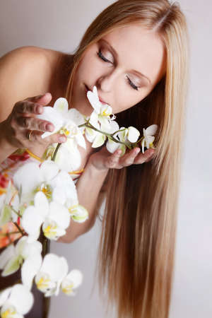 Beautiful blond girl with orchid flower in studioの写真素材