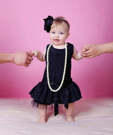 Little girl holding parents hands on pink backgroundの写真素材