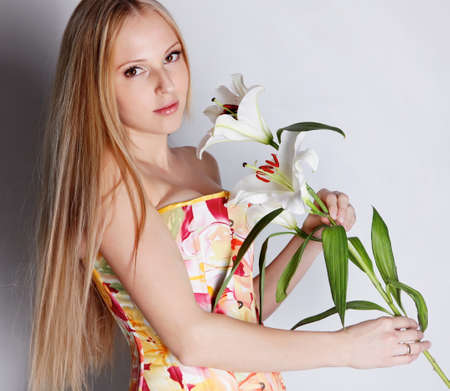Beautiful blond girl in color dres with lily flowerの写真素材