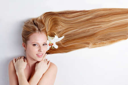 Beautiful blond girl with lily flower in hairの写真素材