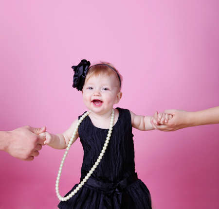 Little girl holding parents hands on pink backgroundの写真素材