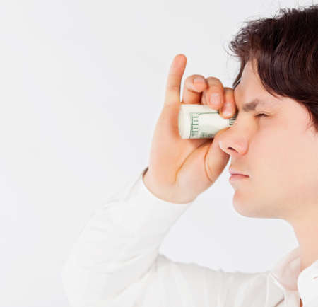 man looking through a tube of dollarsの写真素材