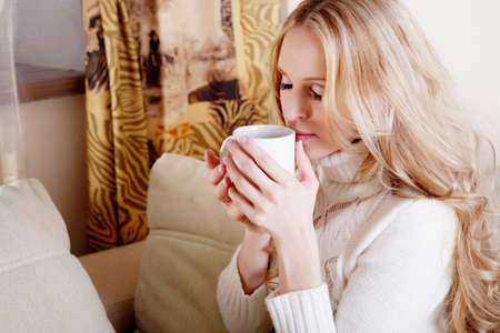 Beauriful girl drinking coffee at homeの写真素材