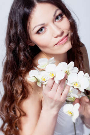Beauriful brunette girl with orchid flowers in studioの写真素材