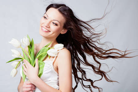 Beauriful brunette girl with white tulip flowers in studioの写真素材