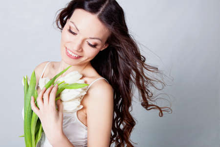 Beauriful brunette girl looking tulip flowers in studioの写真素材
