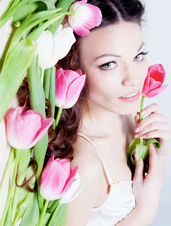 Beauriful brunette girl laying in bed with tulip flowersの写真素材
