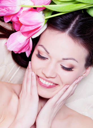 Beauriful brunette girl laying in bed with tulip flowersの写真素材