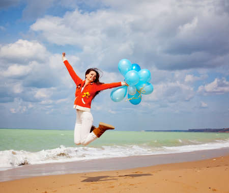 Girl on the beach with balloons in handの写真素材