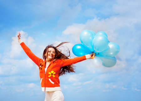 Girl with balloons under blue sky with cloudsの写真素材