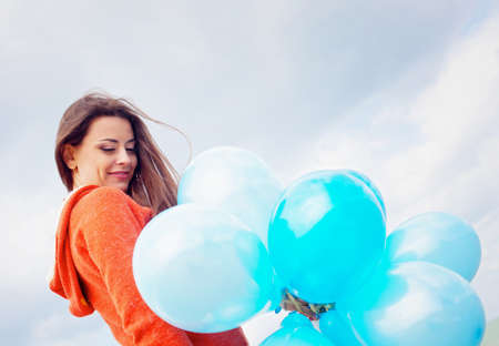 Girl with balloons under blue sky with cloudsの写真素材