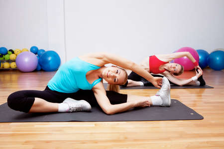 Two girls stretching in fitness clubの写真素材