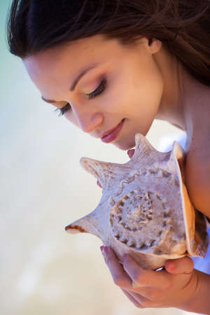 Beautiful girl with seashell in handの写真素材