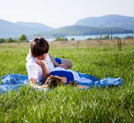 Two lovers lying on the grass near mountain lakeの写真素材