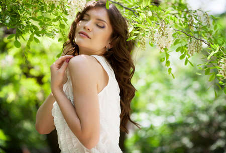 Beautiful girl under blossom acacia treeの写真素材