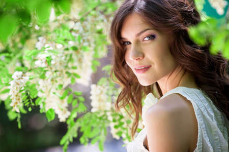 Beautiful girl under blossom acacia treeの写真素材