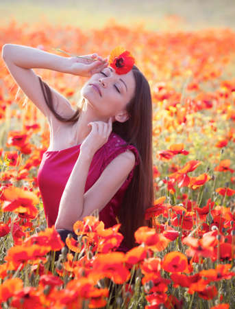 Beautiful girl in poppies meadowの写真素材