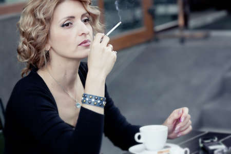 Woman with cup of coffee in summer cafeの写真素材