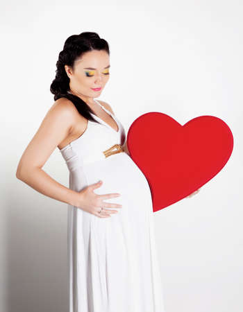 Beautiful pregnant woman with big heart in handsの写真素材