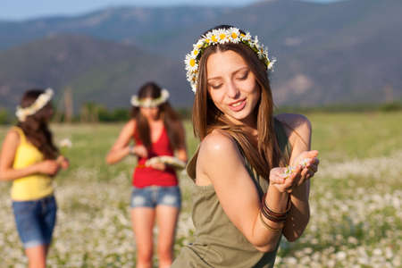 Three girlfriends on camomile meadowの写真素材