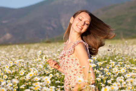 Girl with flowers in hand on camomile meadowの写真素材