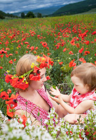 Mother with daughter on the poppy meadowの写真素材
