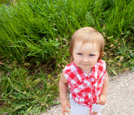 Child standing on the road near the grass fielsの写真素材
