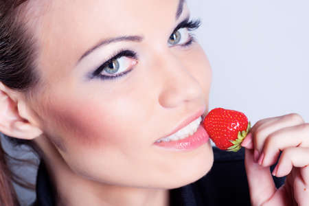 Beautiful girl eating strawberry in studioの写真素材