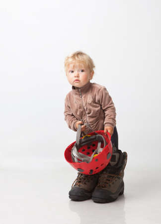 Little girl in big boots and helmet in handsの写真素材