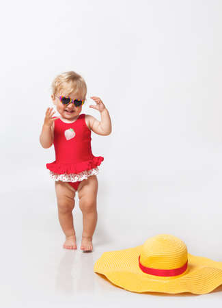 Little girl in sunglasses with big hat in studioの写真素材