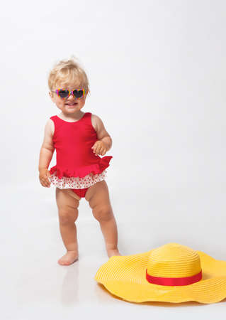 Little girl in sunglasses with big hat in studioの写真素材