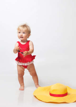Little girl in sunglasses with big hat in studioの写真素材