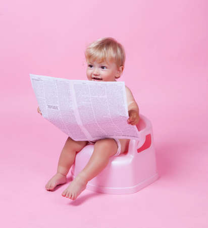 Little girl with newspaper on the potの写真素材
