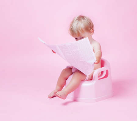 Little girl with newspaper on the potの写真素材