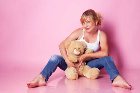 lovely woman in jeans on a pink backgroundの写真素材
