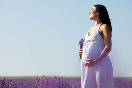 long-haired pretty pregnant woman in a lavender field